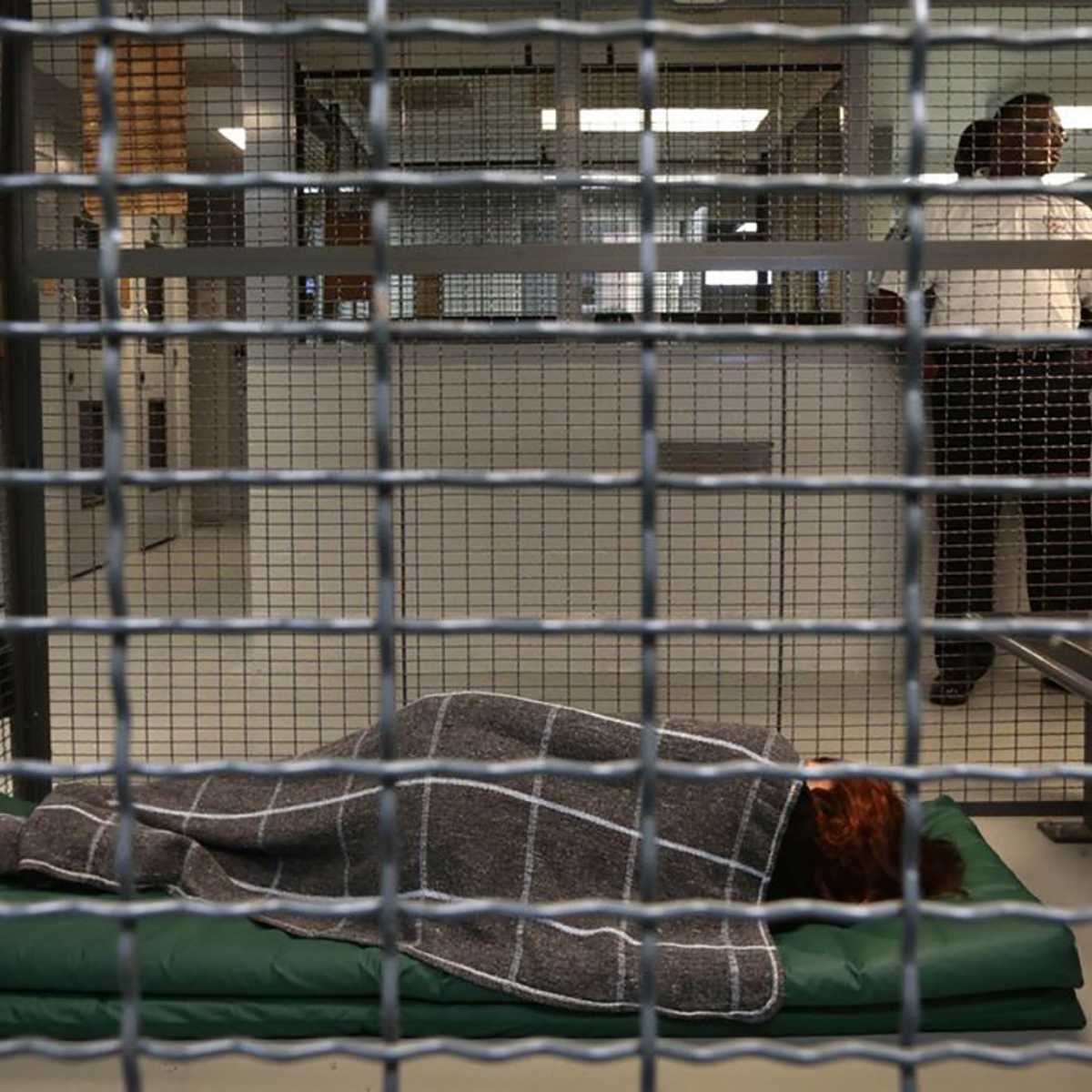 person sleeping on mat inside of wire mesh cage