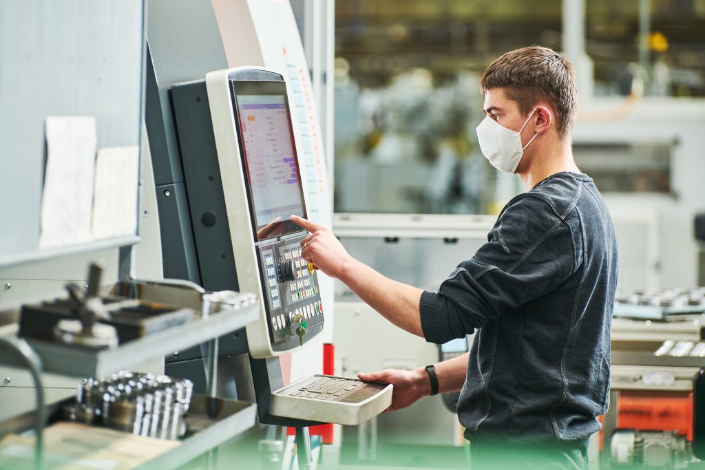 Worker operating machine in protective mask